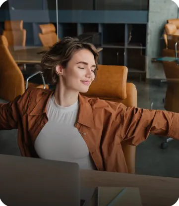 A woman stretching in her chair at a desk in a quiet office