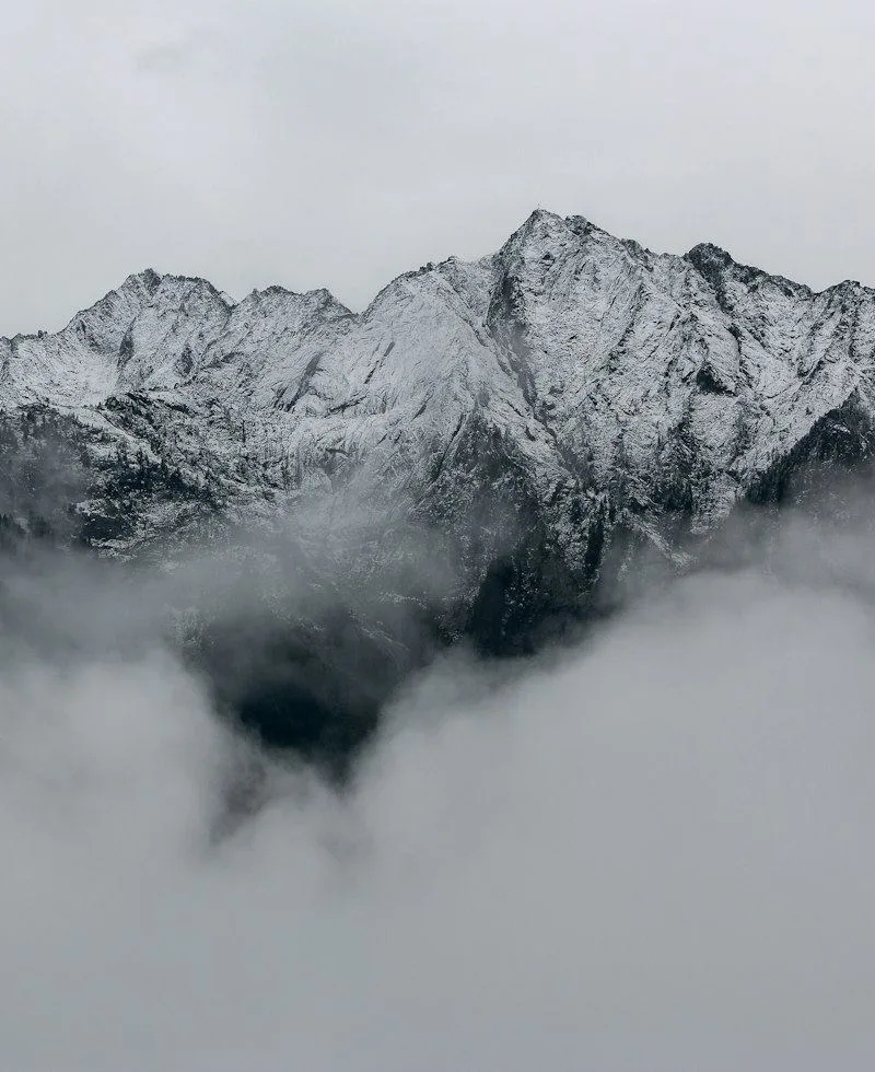 Snow-capped mountain peaks rising calmly above the clouds